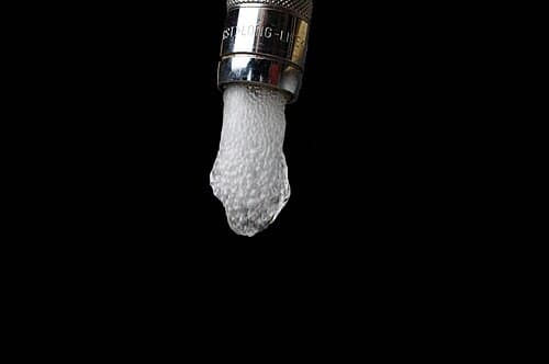 Torneira com gota de água prestes a cair