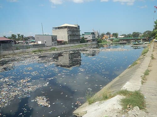 Resíduos plásticos acumulados na margem de um rio